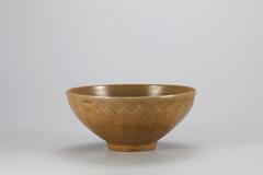 <p>This type of bowl was extensively produced throughout the 12th century. The outer wall is decorated with incised and raised deisgn of a two-tiered lotus petal. The glaze was oxidized, producing yellow-green color, but the application of glaze to the entire foot and the use of quartzite spurs indicate that this was produced as a high-quality item.<br />
[<em>Korean Collection, University of Michigan Museum of Art</em> (2014) p.103]</p>
It has a wall gently curving from the mouth toward the bottom before angeling in sharply close to the foot. There is a lotus petal on exterior. The color is brown.