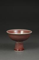 This oxblood stem cup has a stout base with a bowl shaped body. There is an interior carving on the bowl and a reign mark on base.