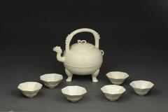 Three legged, soft paste porcelain tea pot with spout, rou-y scepter on lid and six soft paste porcelain tea cups, six sided with interior and exterior incising.