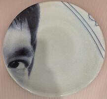 A plate from the center of the piece. A man&#39;s left eye and forehead are visible in the left side of the plate.&nbsp;