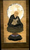 This hanging scroll shows a monk seated cross-legged on a lotus pedestal with his head and shoulders surrounded by a white halo. He is dressed in black robes, with a white, geometrically patterened kesa. He holds a Buddhist rosary in both hands, and looks downwards into the distance. 