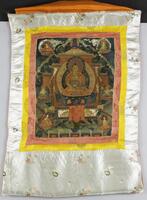 A portable painting (thangka) in gouache and gold pigment on sized cotton, framed with concentric borders of red and yellow figures silk, with an outer border of white satin with embroidered floral designs. The painting is designed to be rolled up when not in use.