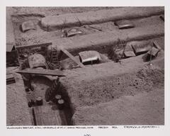 Multiple cars under excavation with excavation supplies, including barrels.