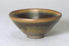 A conical bowl on a straight foot ring, covered in a thickly applied dark, iron-rich brown-black glaze with subtle hare's fur markings (兔毫盏 <em>tuhao zhan</em>).  