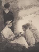 Four women pose in an outdoor setting. Three women sit on the ground in light dresses, one reads and the other two look toward her book. One woman stands, leaning against a tree that frames the left-most side of the image; she wears a dark dress, her back turned to the viewer.
