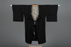 <p>Black silk michiyuki with dark grey interwoven water and wave (mizunami) motifs with a light gray silk lining with interwoven shikunnshino maru (floral motifs arranged in a circular shape) motif patterning.</p>

