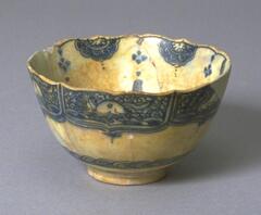 This bowl was modeled on a Chinese vessel of the late 16th century. Below the foliate rim there are six panels with horses in reseve against a background of waves and clouds. Following the system used on Chinese vessels the horses facing different directions are placed in alternation around the bowl. Small tassels hang from the center of each panel, but otherwise the middle zone of the exterior is free of decoration. Overlapping petals are found just above the foot. The internal decoration consists of a floral spray in the foot and eight half-medallions on the rim separated by eight tassels hanging from the rim. <br /><br />
 