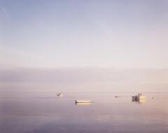 Photograph of boats in the middle of a calm body of water.