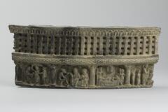 A curved stone, originally a facing on the drum of a small stupa, carved with a narrative scene.