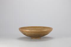 <p>The beginning of the 14th century saw a change in inlaid patterns from using both black and white clay to only using white clay, as demonstrated by this bowl. Concentric white circles extend around the upper and lower parts of the inner and outer surfaces, while the inner wall features a chrysanthemum design in three places. Sand is stuck to the foot and the outer base. The bowl is tinged with vivid yellow. Parts of the rim are slightly damaged, but the glaze is finely fused.<br />
[<em>Korean Collection, University of Michigan Museum of Art </em>(2014) p.107]</p>
