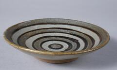 Shallow dish with repeating circles of gray, black, and white glaze.