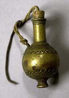 A brass container with a round body and a short neck. The stopper is connected to the bottle by a string, to which a small metal scoop is attached. The body of the container is decorated with a grid-like pattern and an undulating line around the top and bottom edge. The top edge of the neck has a rope or braid-like pattern. 