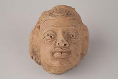 Indian terracotta sculpture of a man's head, craft with details with opened eyes, nose and mouth.