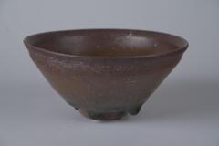 A brown teabowl with four small feet.