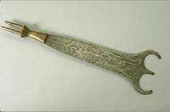 The wooden handle of this sword has two sharp projections at its end. The blade is wide and has a double-arched end. 