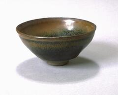 This deep, conical bowl on a straight foot ring is covered in a thickly applied dark, iron-rich black glaze with lighter, russet-brown hare's fur (兔毫盏, <em>tuhao zhan</em>) markings.  The thick glaze thins at the rim to a russet-brown color.