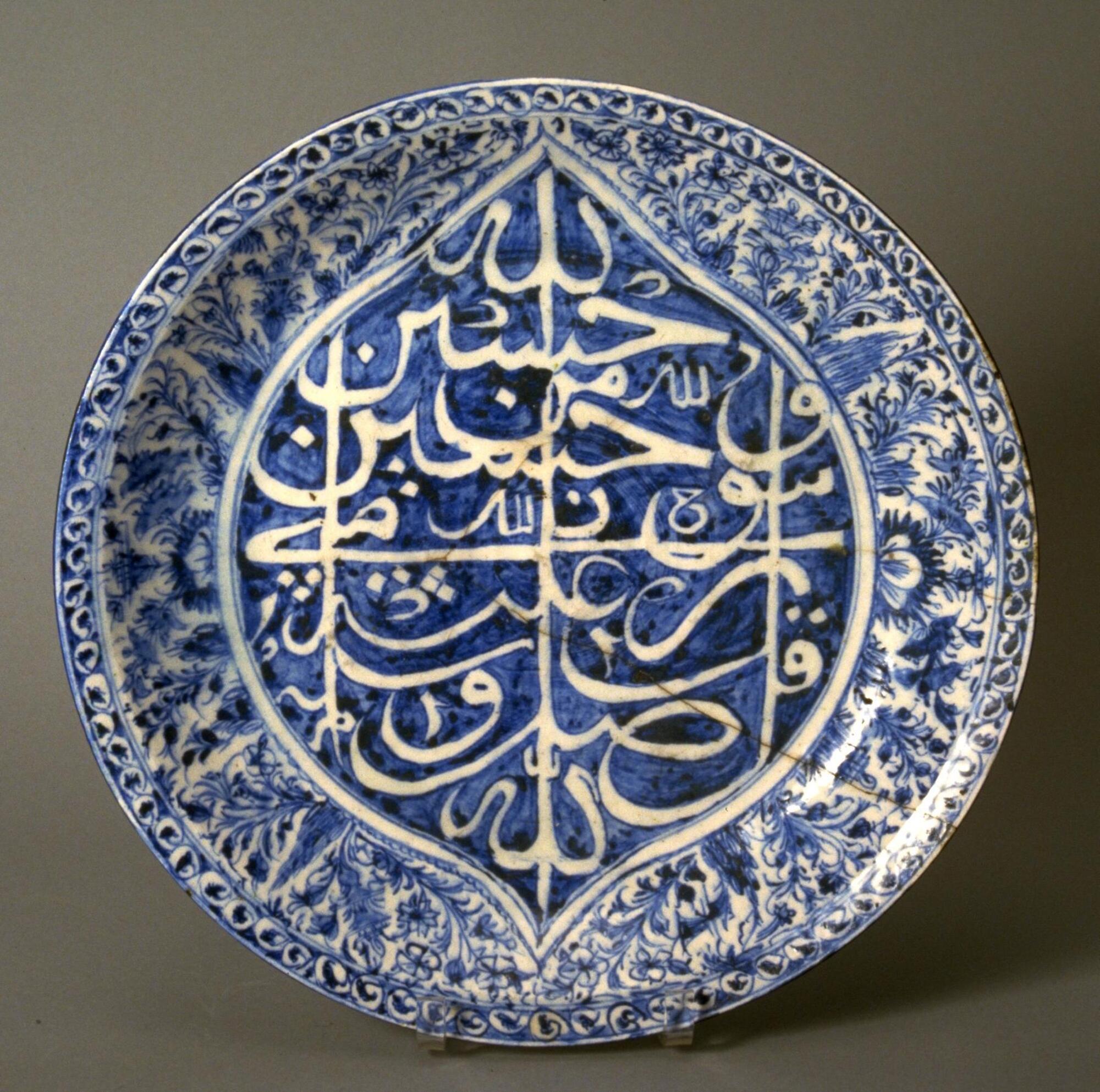 A blue and white platter. White porcellanous body with painting in blue under a clear glaze slightly tinged with blue-green.