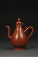 Porcelain coral-color glaze&nbsp;ewer that has a wide, thick base, a teardrop shaped body with a long curvy spout and handle, and a point at the top. It has a studio mark on the base.