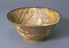 Deep bowl with a wide base and slightly everted rim decorated in amber glaze.