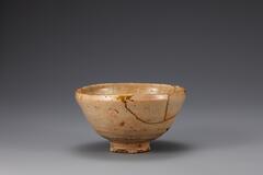 The mouth is straight. The side is gently curved to the bottom. The foot is hgh and narrow. It was repaired.<br />
<br />
Produced between the 15th and 16th century at a privately owned kiln in the southwestern region of Gyeongsangnam-do, this bowl has been restored following breakage into ten pieces. Its rim curves inwards. It is made with stoneware clay. There are five spur marks on the inner base, and the glaze on the rim of its foot has been wiped away. It is coated with opaque white glaze, on which have formed many crackles and pinholes. The color of glaze is not even throughout the surface. Vessels of this type were popular in Japan as tea bowls (茶碗, Jap. chawan).<br />
[Korean Collection, University of Michigan Museum of Art (2014) p.160]