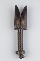 Staff with a cylindrical handle, decorated with zig-zag patterns, and a disc-shaped grip at the bottom. The top of the staff has two identical faces on both sides, surmounted by a double axe shaped form. 