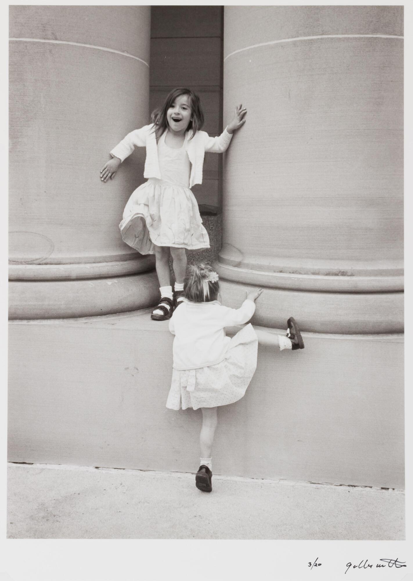 Two girls in white dresses and sweaters climbing on large concrete pillars. one is climbing up, the other is posing.
