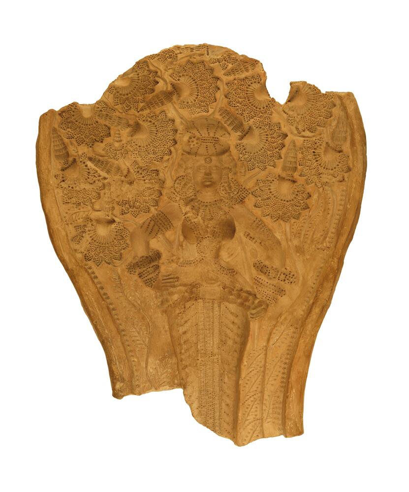 This is a wood-colored, stump-like figure that is narrower on the bottom and blossoms towards its top. The surface has multiple, engraved designs. The top and bottom have jagged edges.
