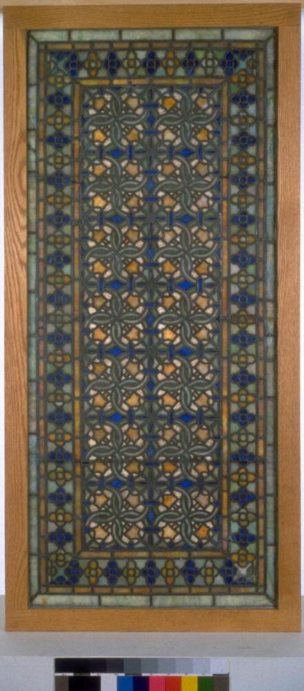 Window in geometric patterns of white, blue, and amber colored glass set in a modern wooden frame