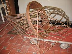 An abstract sculpture made out of wood. Composed of three parts with a wooden ring encircling the other two additions.