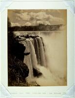 Taken from a rocky ledge, this photograph depicts a view of a large waterfall surging over a cliffside.