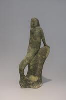 A figure carved in pale green stone of a mermaid leaning on a rock with one hand behind her.&nbsp;