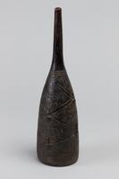 Hollowed cone-shaped vessel with a thinly tapered, extended tip. Vessel is designed with various geometric shapes including repetitive diamond and square patterns.