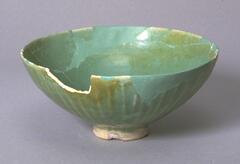 A conical deep bowl with missing rim section.