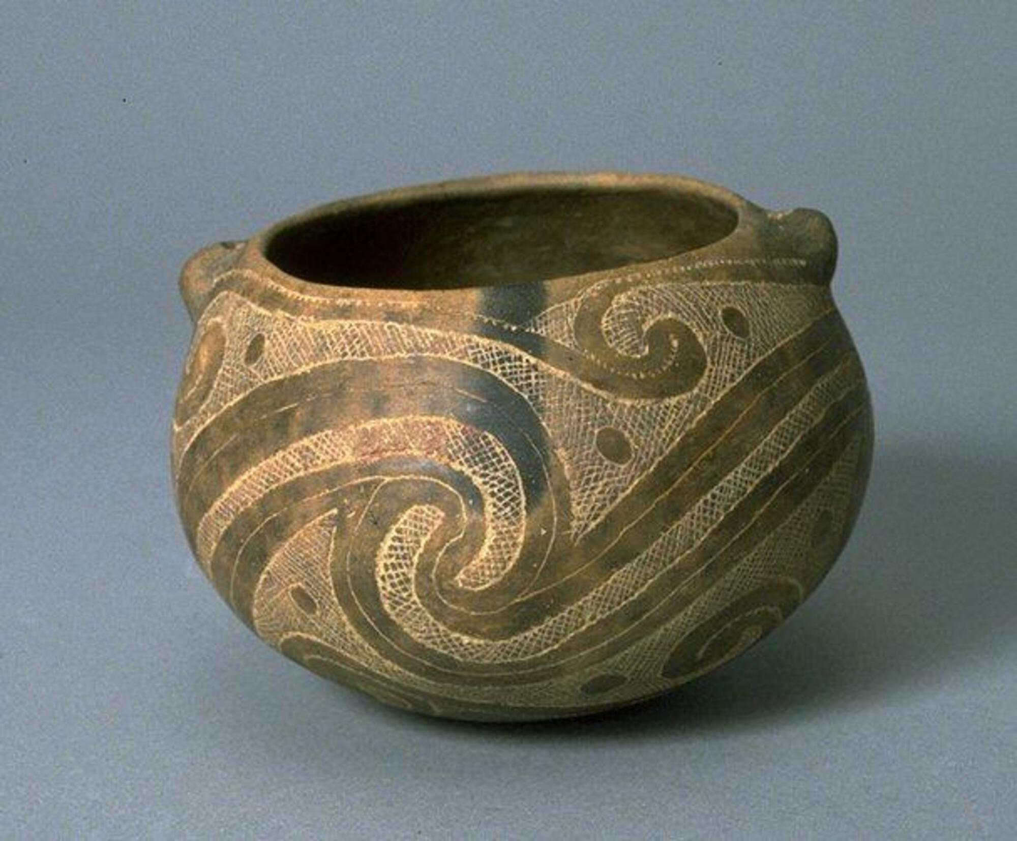 Bulbous bowl in dark and light browns on the outside, black interior. Patterns of scrolls, circles, and dots around the exterior.