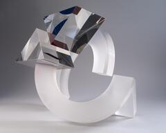 A large abstract glass sculpture with a circle broken into two equal pieces and two triangles. The triangles are transparent and the circle pieces are frosted.