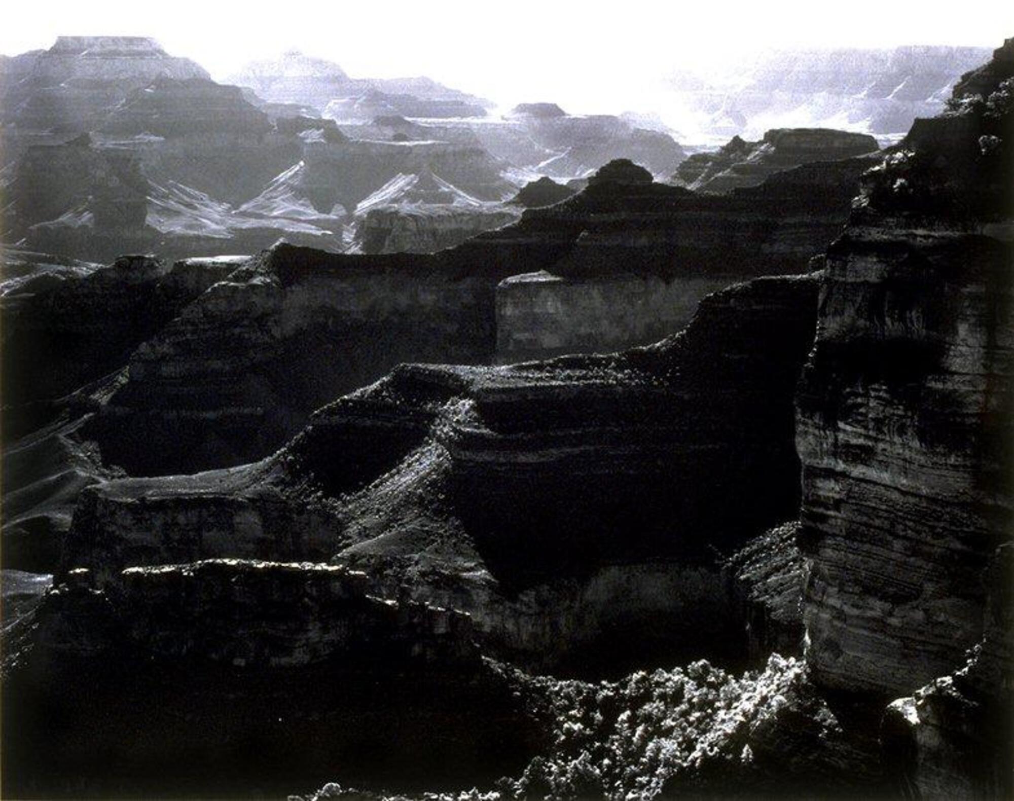 Taken from a high vantage point, this photograph depicts a view of a vast desert canyon. The ridges of the canyon extend into the distance.