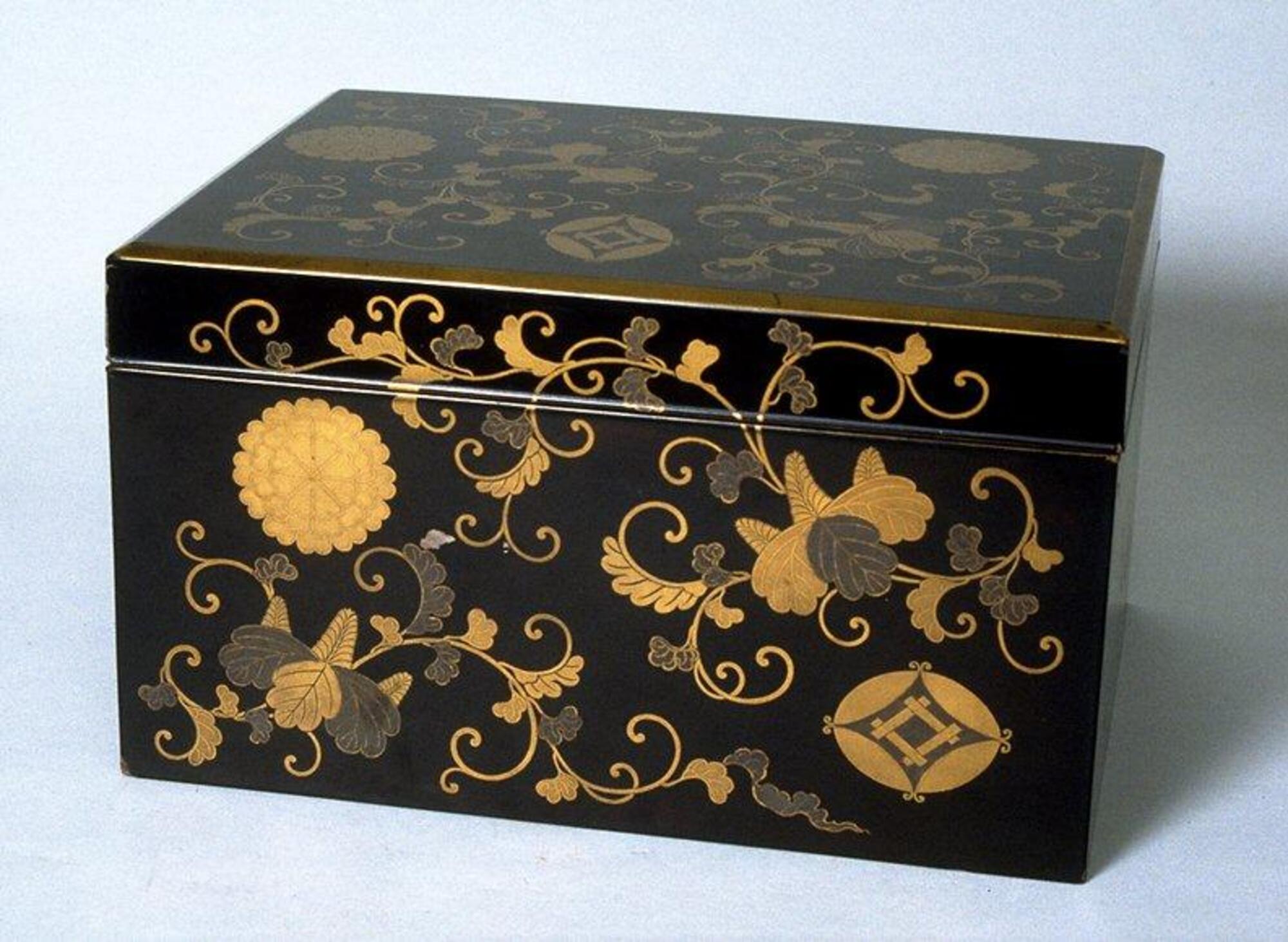 The box is covered in detailed floral patterns in lacquer on a black background, with a family crest in the lower right corner of the front and top of the box. Part of a bridal trousseau.