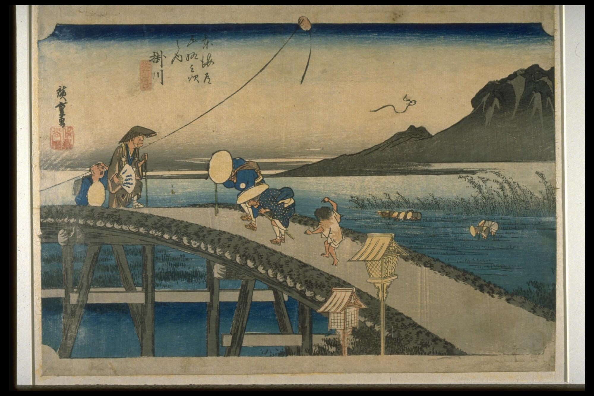 A bridge forms a diagonal on the print. Three travellers are passing the bridge, while two monks are walking down toward them. Landscape of water and mountains is shown in the background.