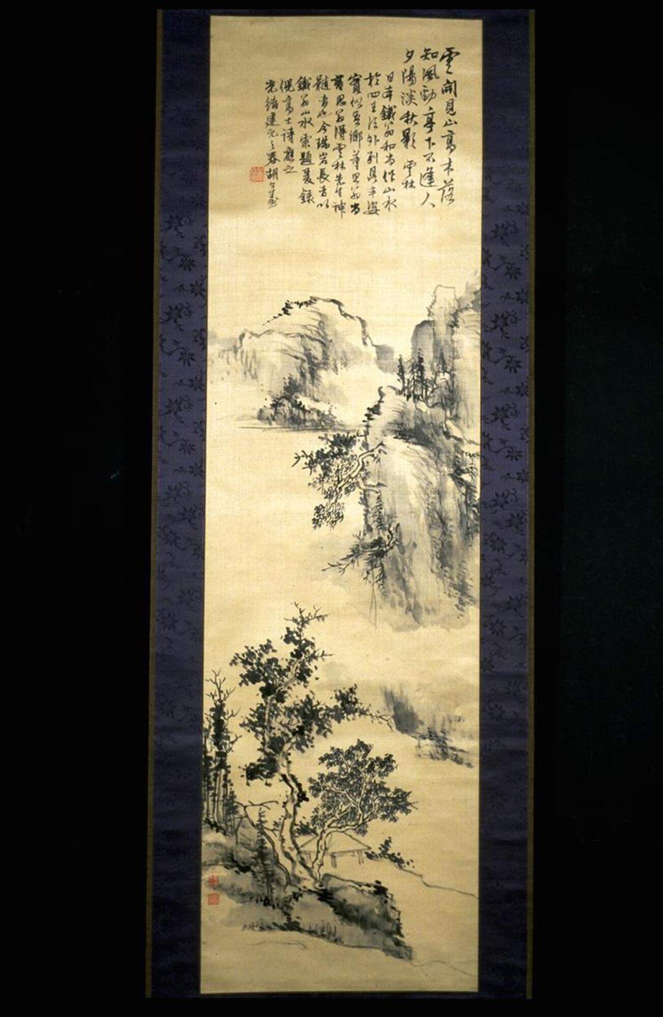 There is a mountainous&nbsp;landscape with trees scattered around and mist in the air. At the top of the hanging scroll, there is an inscription and a seal.