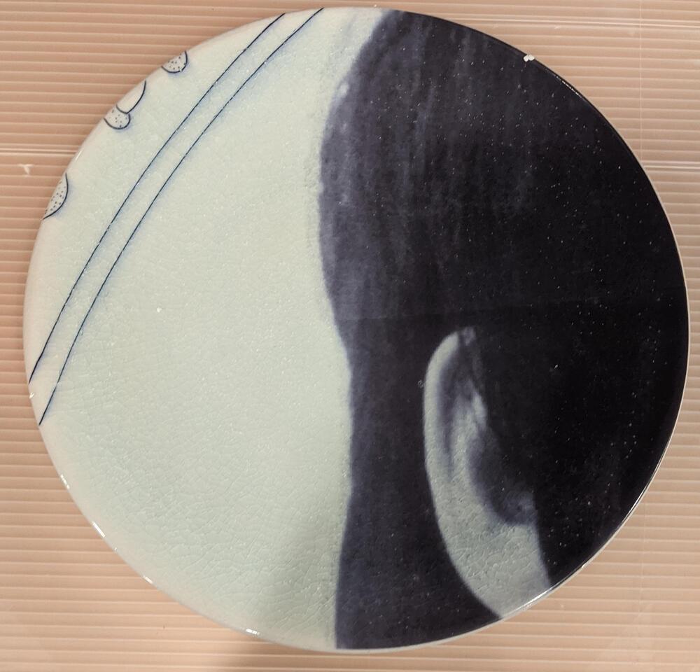 A plate from the center border of the piece. The right half of the plate depicts the side of a figure&#39;s head with dark hair and a visible ear.&nbsp;