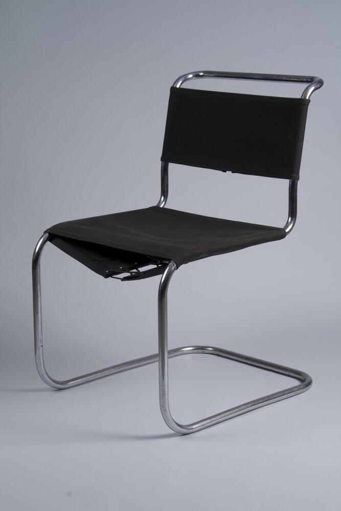 Cantilever chair frame formed by a continuous line of thin steel tubing (connected under the seat with an additional piece of tubular steel), with separate lengths of black canvas wrapped around it at the seat and back.