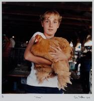 A girl holding a hen in both of her arms, looking directly into the camera.