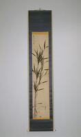 Bamboo leaves are rising from the bottom left corner of the hanging scroll. There is a signature and two seals in the top left corner of the hanging scroll and another seal in the bottom left corner. There is a green border surrounding the hanging scroll.