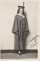A portrait of a young woman in a graduation cap and gown. She stands in front of a striped wall. The front of the image is signed in ink.