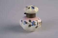 A porcelain inkwell with rounded corners. Painted flowers and butterflies decorate the base and the lid. The flowers are blue while the butterfly is gold.