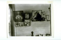 An interior wall adorned with various framed photographs of family members and religious icons. 