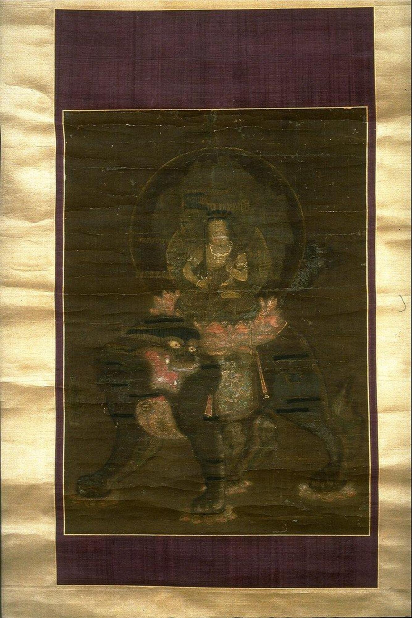 This icon painting depicts the bodhisattva Monju seated cross-legged on lotus on top of a lion. The figure holds a vajra sword, and is dressed in flowing robes with golden jewelry. Two circular mandorlas surround the figure. 