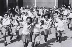 A group of young girls and boys rush toward the camera with smiles on their faces and hands outstretched.