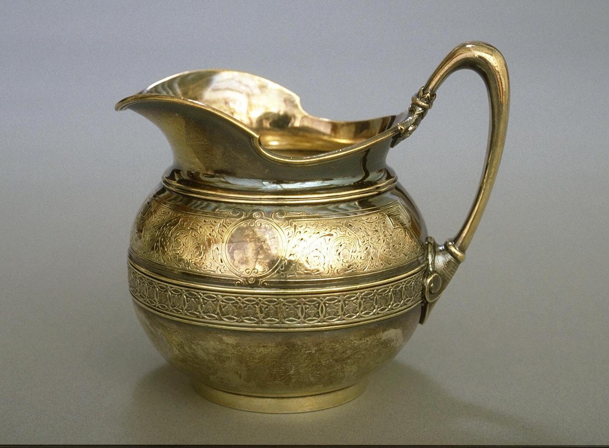 Silver pitcher-shaped vessel with handle and a band of decoration around center of the body