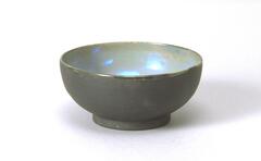 Footed bowl-shaped vessel covered with an iridescent glaze over a semi-matte glaze in gray-ish blue